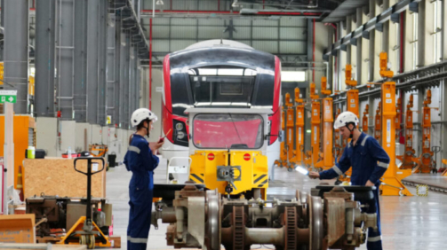 Engineers inspecting locomotive in railway engineering facility